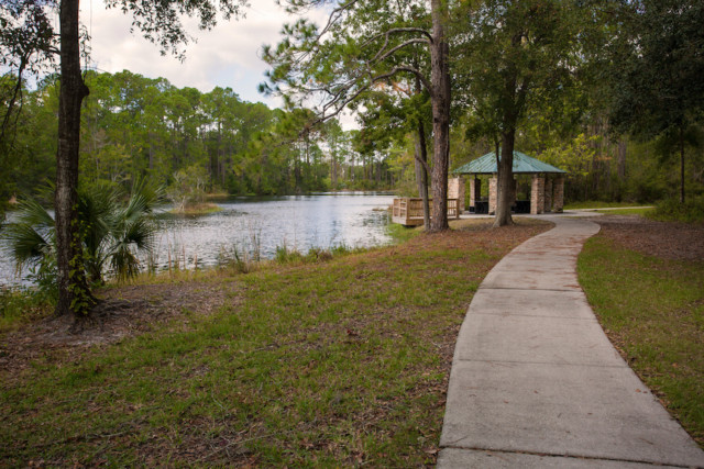 Sidewalk on right leads to pavilion with lake on the left.