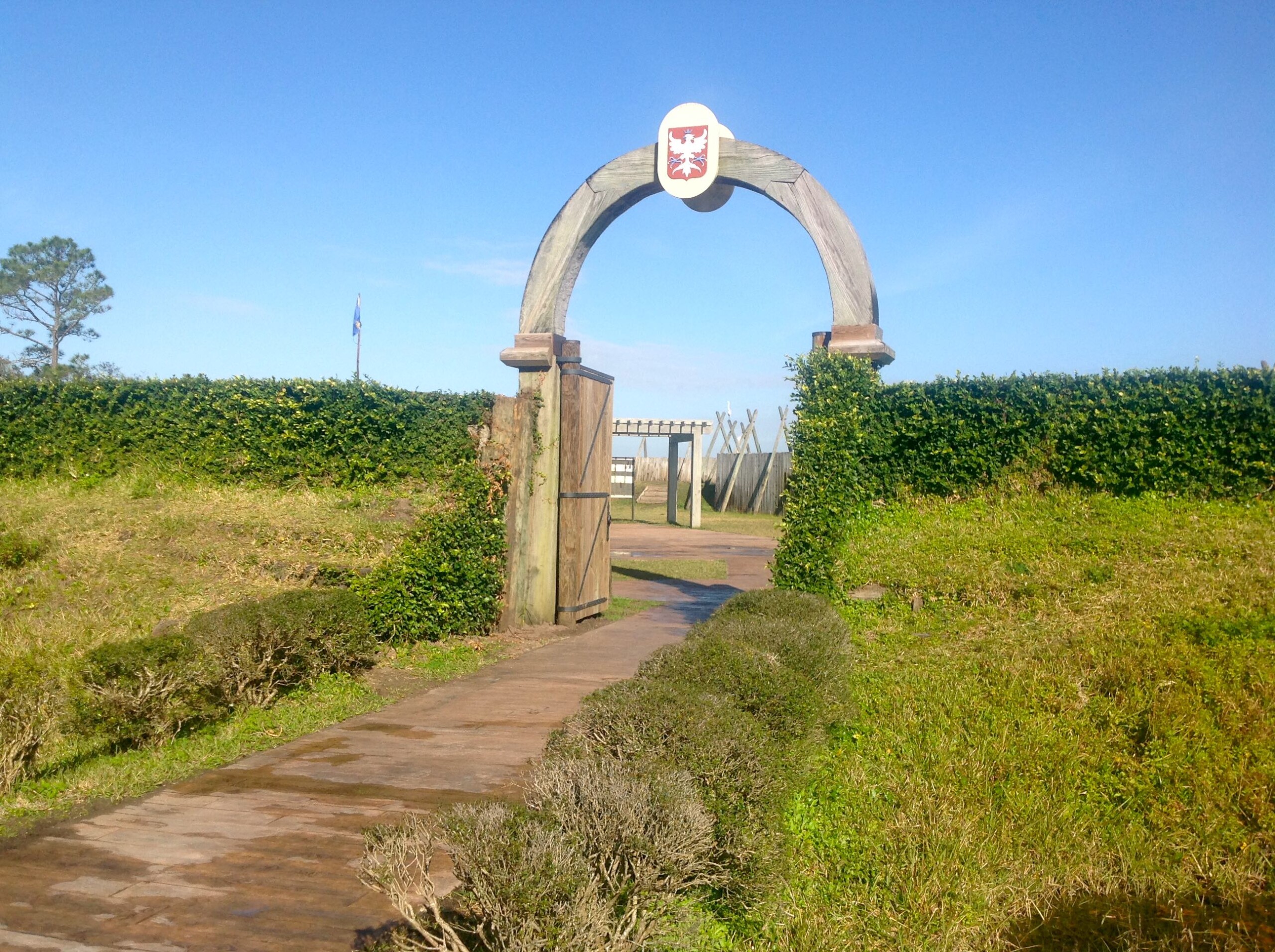 Oversize wooden gate in the middle with grass covered embankments on either side