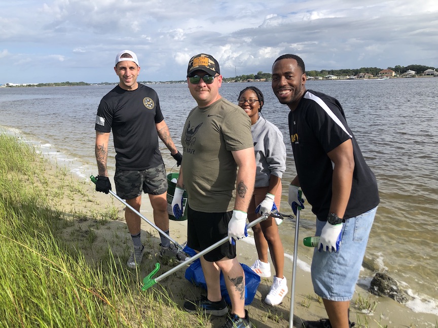 Four volunteers at shoreline collecting litter