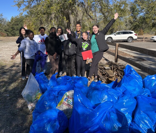 Group of young people at a park in front of a pile of filled trash bags