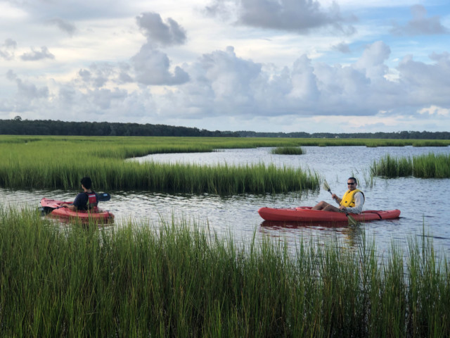 Two men in orange kayaks paddling on the creek