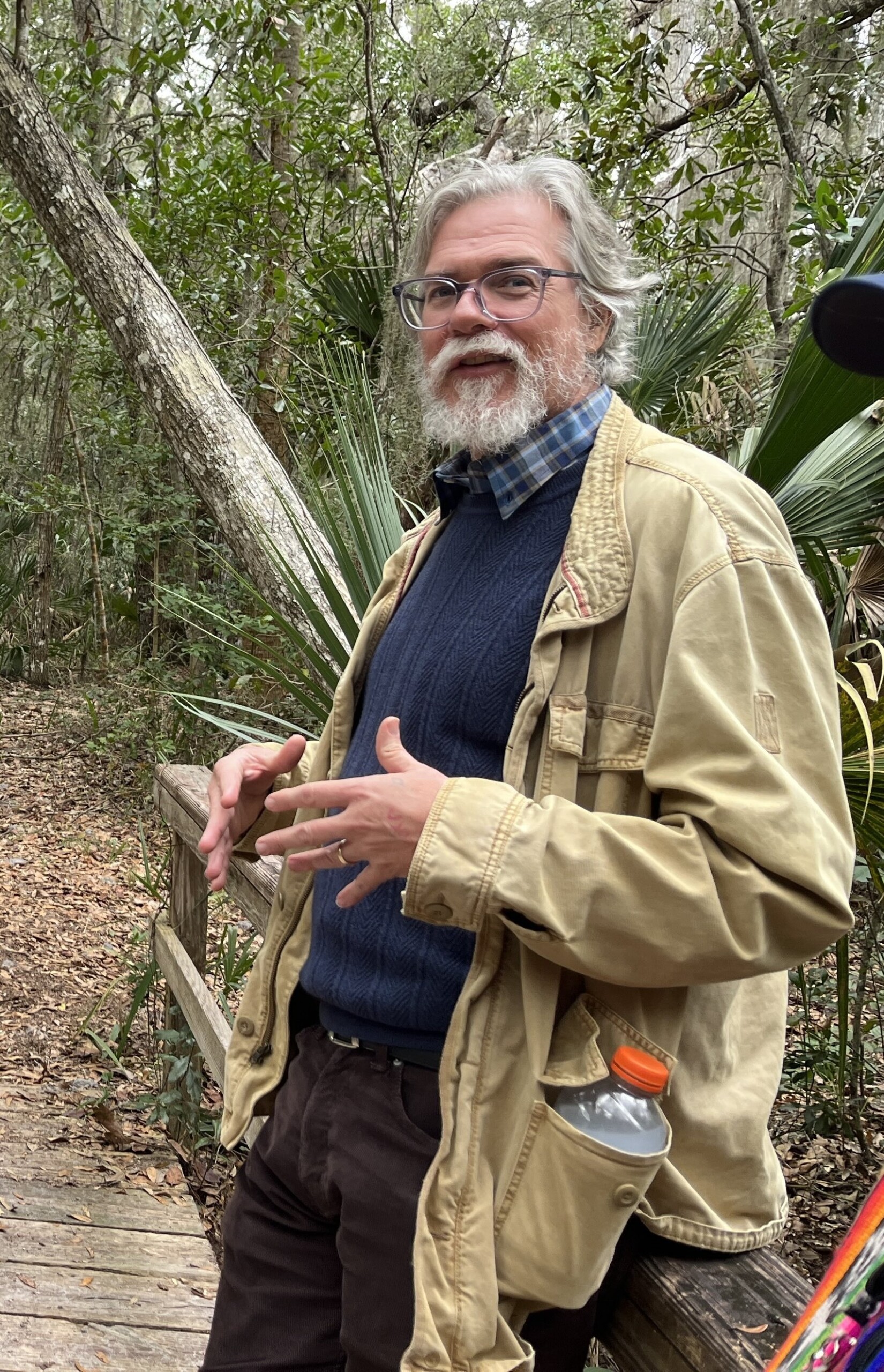 Man in coat standing on boardwalk on trail